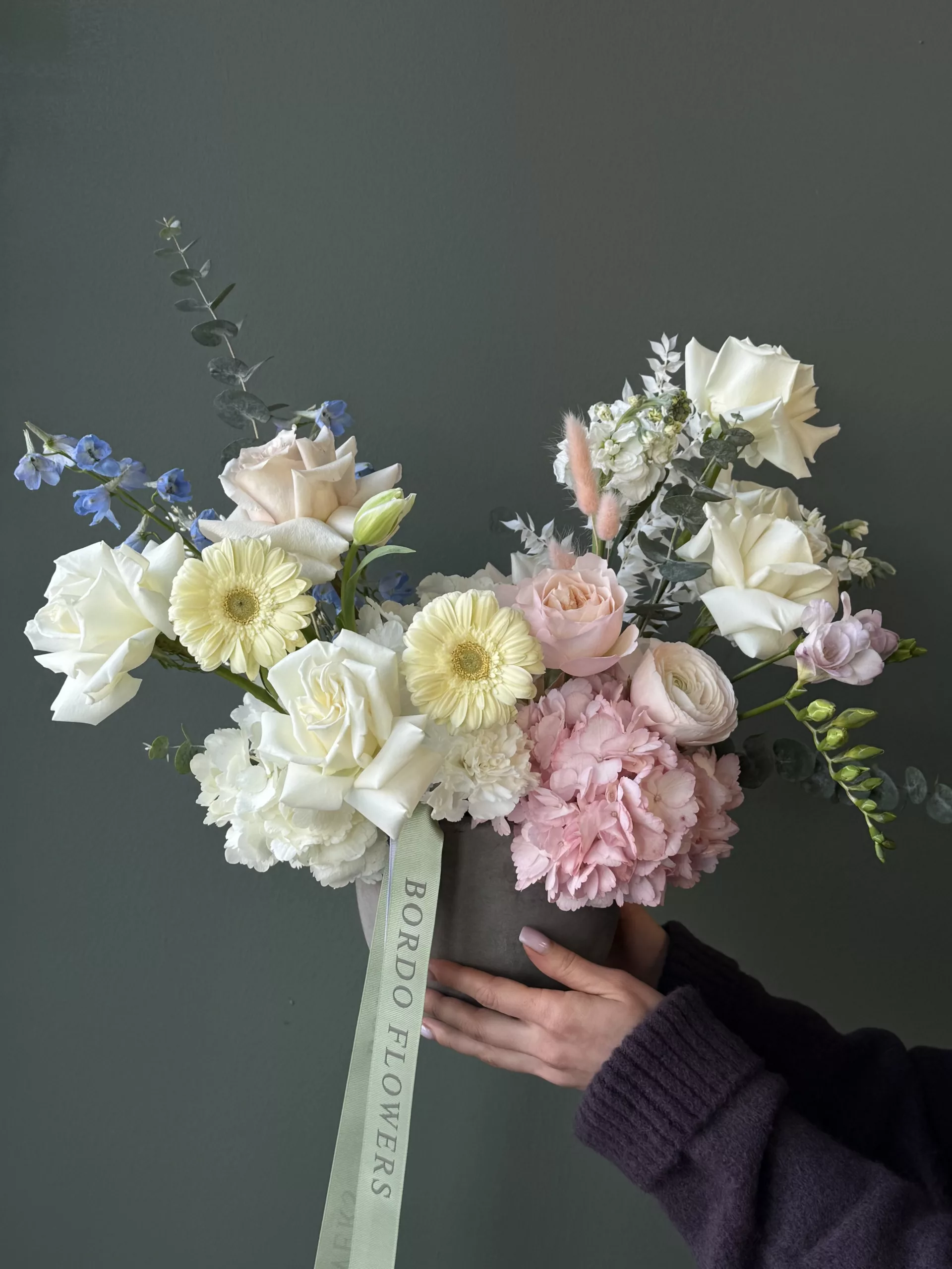 Vase "Lacy Bird" Vase "Lacy Bird" – a sophisticated statement of timeless elegance in soft pinks and whites, created in a sleek, modern grey beton vase. This premium arrangement combines the delicate beauty of ranunculuses and garden roses, blending their lush petals for a refined and luxurious look. Perfect for adding a touch of elegance to any space, Vase Bloom is part of our exclusive collection, capturing the essence of understated beauty and refined taste.