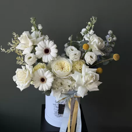 "Sun and Sea – Summer Edition" Embrace the warmth of the season with Sun and Sea – Summer Edition, a radiant spring-to-summer arrangement bursting with soft butter yellow blooms and white flowers, gently balanced by blue  accents. This stunning display captures the essence of sunny days and coastal breezes, exuding both elegance and sweetness. Each bloom is carefully curated and thoughtfully arranged to create a harmonious blend of color and texture, making it a perfect gift or a standout centerpiece for any occasion. Presented in a charming baby blue box, and adorned with multiple tones of blue ribbons, this arrangement adds a playful yet sophisticated touch to any space.